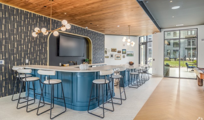 large kitchen area with modern lighting and barstools